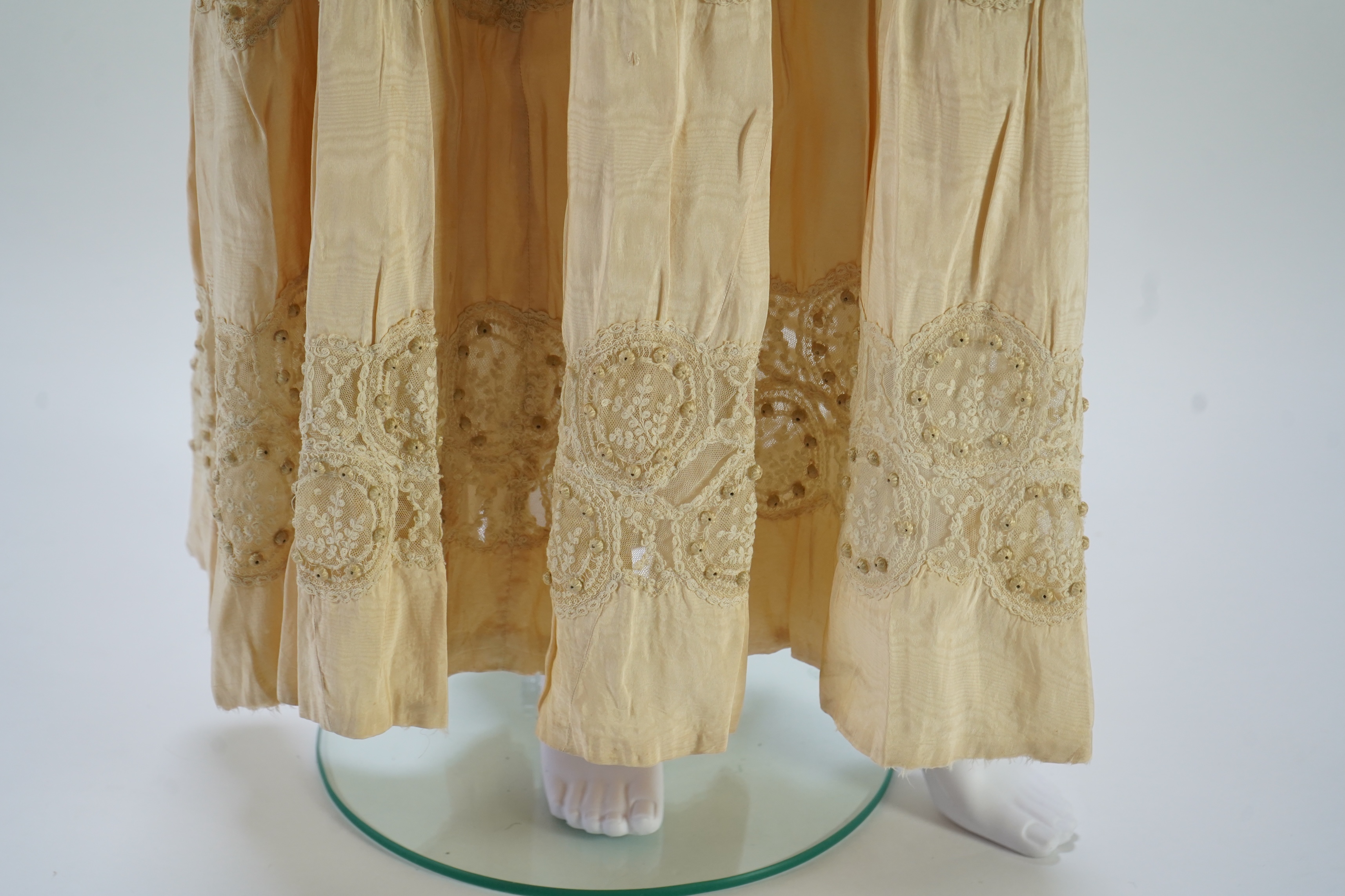 A suitcase containing a cream silk lace skirt to a dress, an Edwardian silk petticoat and various collars, possibly for theatrical use, silk petticoat 96 cm long. Condition - fair